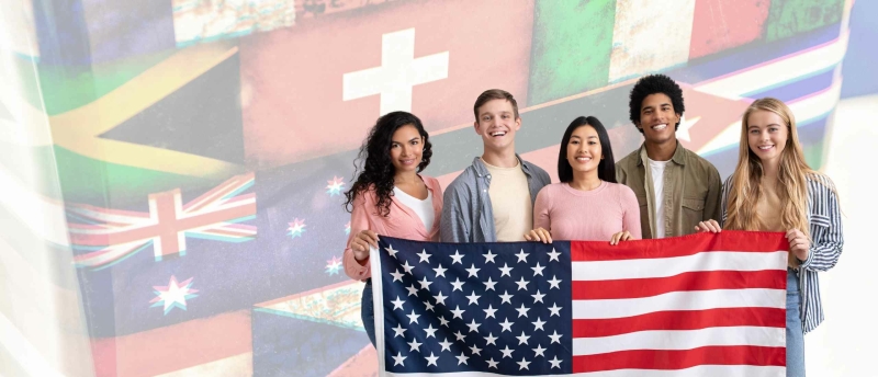 5 expats holding the American flag, with a lot of international flags at the background