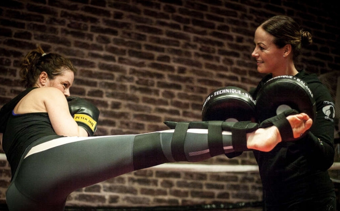 Foto van vrouw aan het kickboksen met personal trainer